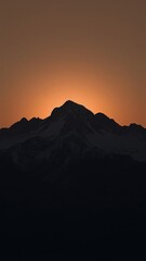 Silhouette of a mountain peak at sunset with glowing orange sky in the background