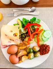 A breakfast plate with eggs, cheese, vegetables and potatoes on a restaurant table. Nutrition, balance, energy and morning wellness in a hotel dining atmosphere. Top view