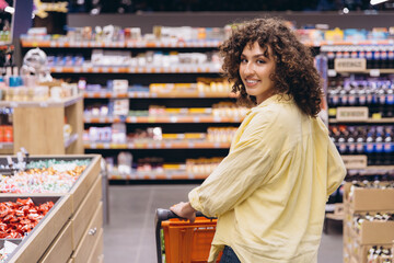 Woman pushing shopping cart in supermarket smiling