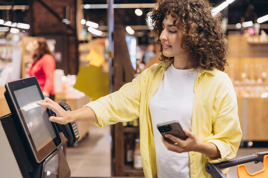 Customer using self checkout kiosk in supermarket