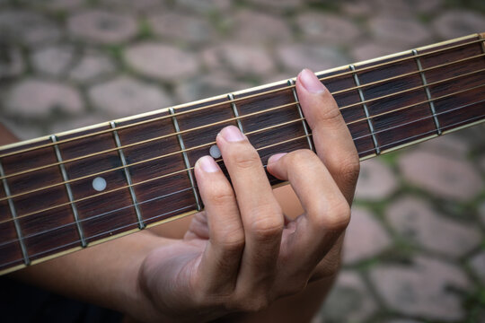 Man's hand is plucking the guitar strings. Man playing guitar.