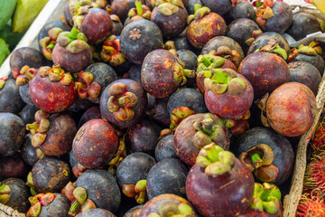 Fresh ripe mangosteens piled in a basket at a tropical fruit market stall. Tropical fruits at Phuket market, Thailand. Close up