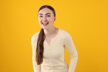 Beautiful woman laughing on yellow background. Positive emotion
