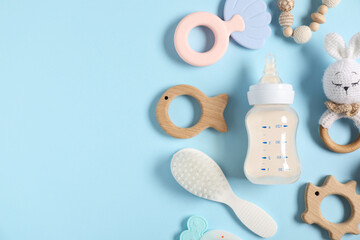 Bottle with milk and baby accessories on light blue background, flat lay. Space for text