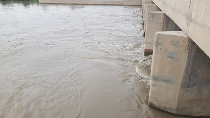 Muddy River Flowing Under a Concrete Bridge
