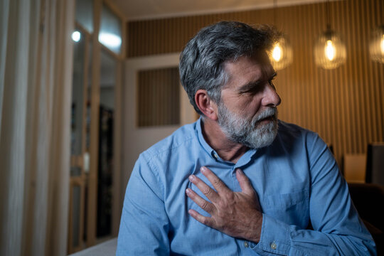 Mature man with sudden chest pain at home in the evening suffering from possible heart attack and serious health problem