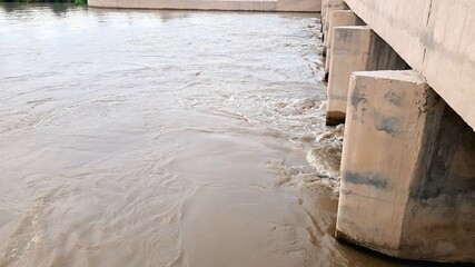 Muddy River Flowing Under a Concrete Bridge