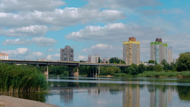 City Bridge and Colorful Apartment Buildings Reflected in Calm River on Summer Day