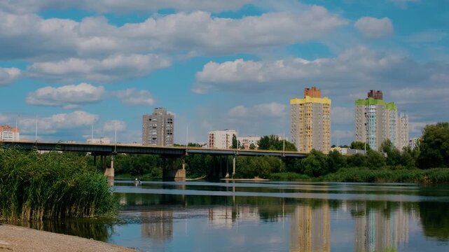 City Bridge and Colorful Apartment Buildings Reflected in Calm River on Summer Day