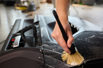 The thorough and effective cleaning process of a car part involves foam and a brush technique