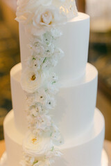 Elegant three-tiered wedding cake adorned with delicate white flowers at a celebration venue