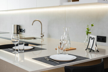 Elegant dining setup in a modern kitchen with well-arranged tableware and soothing lighting during the evening