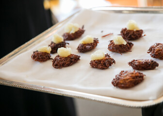 Fine culinary presentation of sweet potato nests topped with cream at a gourmet event in a modern venue