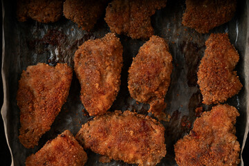 Close-up view of crispy fried chicken nuggets coated in golden batter. High-calorie fast food meal rich in fat and oil. Unhealthy snack or comfort food often associated with junk food