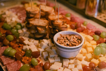 Cheese, meat, and bread platter displayed at a gathering with fresh fruit and nuts in an inviting setting