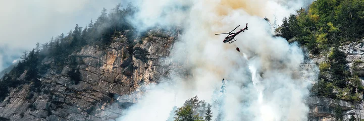 Selbstklebende Fototapeten Hubschrauber Helicopter Firefighting over Smoky Forest Wide Banner  © Аrtranq