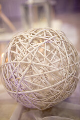 A captivating spherical design made of intertwined twigs rests elegantly on a table, reflecting soft, ambient light from nearby candles during a chic indoor event.