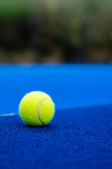Padel tennis ball closeup on outdoor court. Blue surface. Sports equipment.