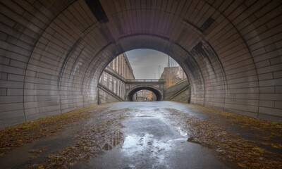 Urban tunnel archway, paved road, autumnal reflections