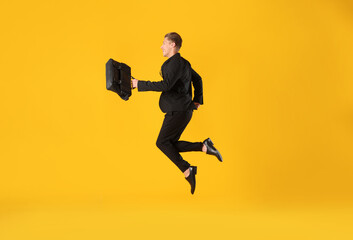Businessman with briefcase jumping on orange background