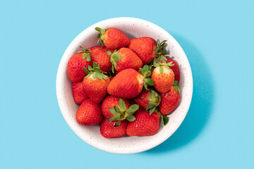 Fresh strawberries in bowl isolated on blue background. Top view