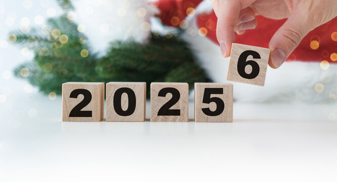 A person is holding blocks that spell out the year 2025 and 2026. The blocks are wooden and arranged in a way that they spell out the year 2026.