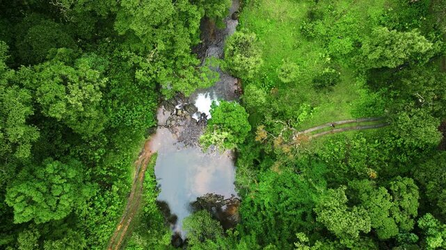 Drone shot of 900 Kandi rainforest in Wayanad, Kerala. A secluded pool of water lies deep in the jungle with mist and fog creating a dreamy monsoon landscape.