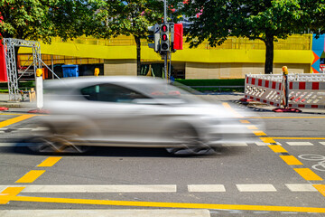 Busy intersection captures a fast-moving car rushing through a traffic light on a sunny day in an urban environment