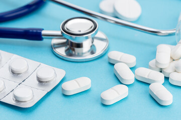 Healthcare medicine background. Close up of Stethoscope and medicine pills on blue background
