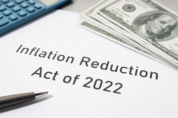 Inflation reduction Act concept. Document, dollar banknotes and calculator on desk