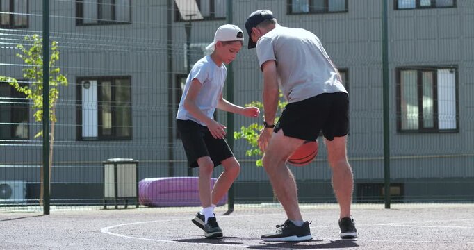 Father and son playing basketball outdoors show family fun and energy. Dad and child playing basketball builds trust and joy. Father and son playing inspires healthy lifestyl bonding. Family sports