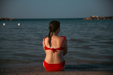 Pretty girl wearing red swimsuit resting on the beach,  summer vacations