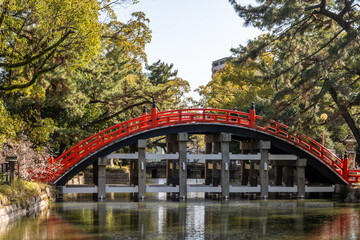 Fototapeta premium Red Sumiyoshi Taisha Sorihashi Bridge is a picturesque red bridge with a high arch that spans a tranquil pond in Osaka, Japan.