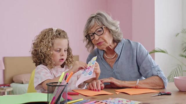 Grandmother teaching granddaughter how to craft stickers in slow motion