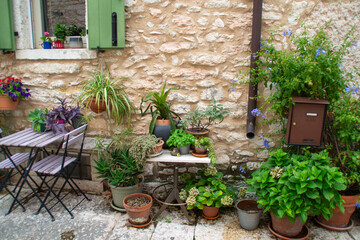 Cozy Mediterranean patio with stone wall, green shutters, flowers, and table set for two