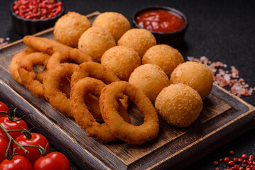 Fast food, cheese balls, onion or squid rings and French fries. Junk food as a background