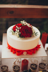 Wedding candy bar with cake, desserts, fruits, and snacks, decorated in red and white colors for a festive celebration.