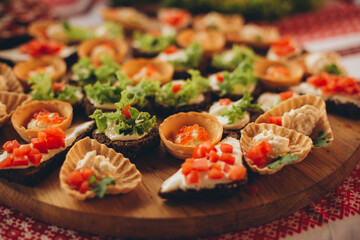 Traditional Ukrainian festive table with assorted appetizers: tartlets, sandwiches with lard, vegetables, and greens. Embroidered towels add authenticity and a cozy atmosphere