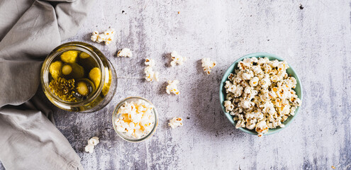 Delicious popcorn with dill and pickles in a bowl on the table top view web banner