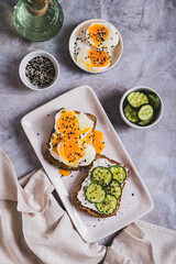 Cereal bread with cottage cheese, boiled egg and cucumber on a plate top and vertical view