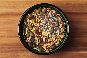Bowl with mixed seeds including pumpkin, flax, sesame, sunflower, and poppy on wooden background. Healthy natural food full of nutrients. Organic superfood ingredients for balanced vegetarian diet.