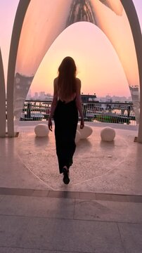 Dubai, UAE, 27.05.2025. Long haired blonde woman walks around Dubai and enjoying Dubai skyline view at Dubai Creek Harbour, Vacation vibe at sunset on a hot summer day.