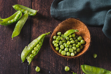 Bowl with green sugar peas on wooden table