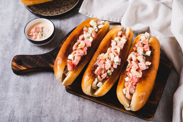 Grilled hot dogs with shrimps, tomatoes, eggs and sauce on a board on a table