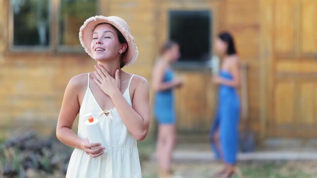 Young woman applying sunscreen outside country house