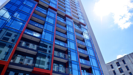 Fototapeta premium Exterior of a high modern multi-story apartment building - facade, windows and balconies. Timeless glass facade. Modern urban living district.
