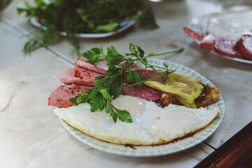 Healthy breakfast of scrambled eggs and sausage, sprinkled with greens, cilantro, dill. High quality photo soft shadows 