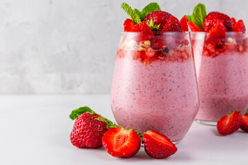 Strawberry yogurt parfait with chia seeds topped with fresh strawberries, granola and mint in glasses on white background. Strawberry chia pudding. Healthy breakfast. Tasty food