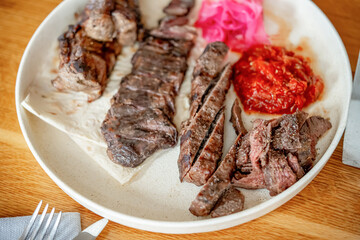 Grilled beef steak, tomato sauce and fresh salad on a wooden table