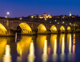 Obraz premium Stone arch bridge at night over still water
